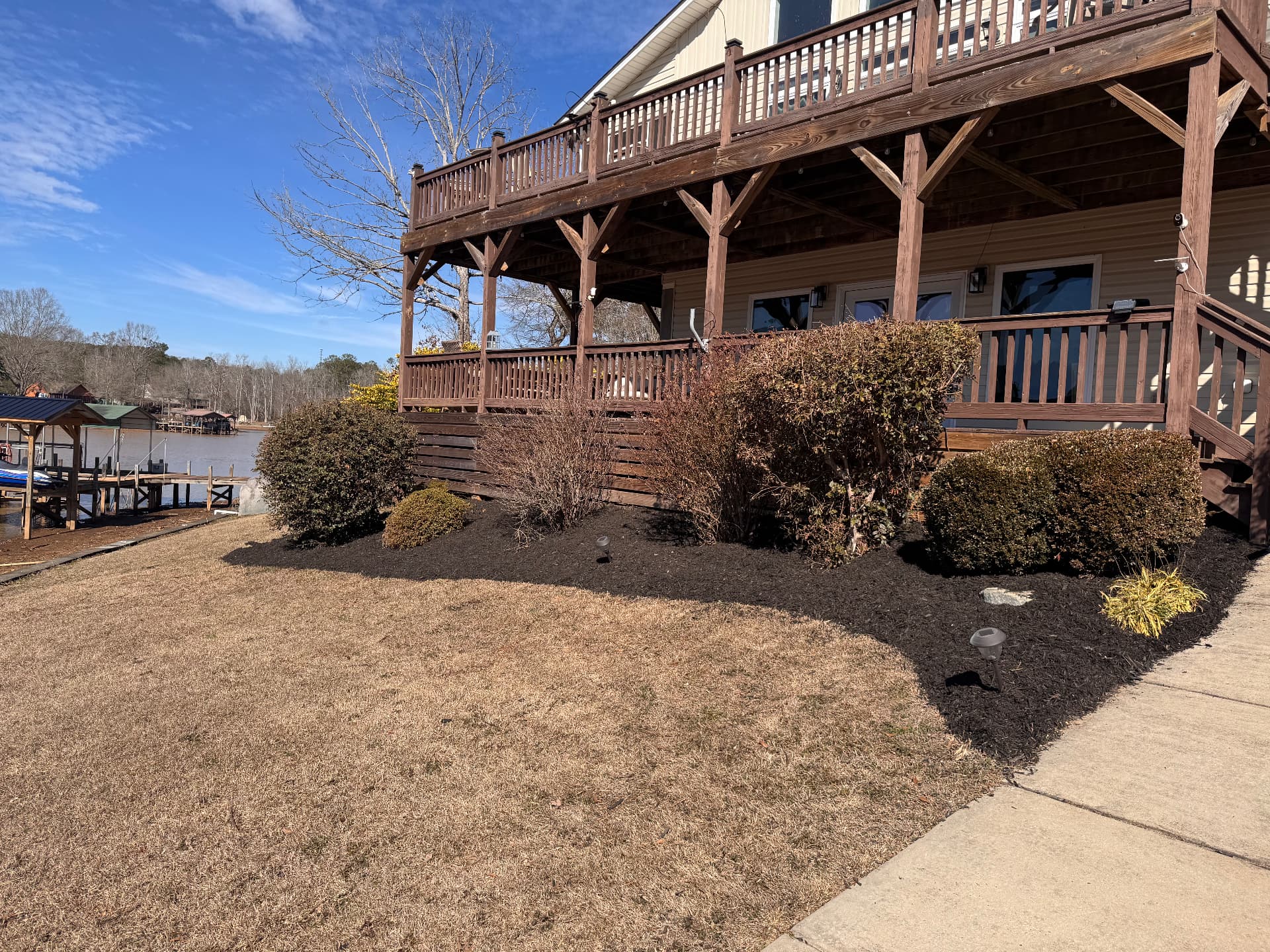 Lake home beds with fresh black mulch and lighting.