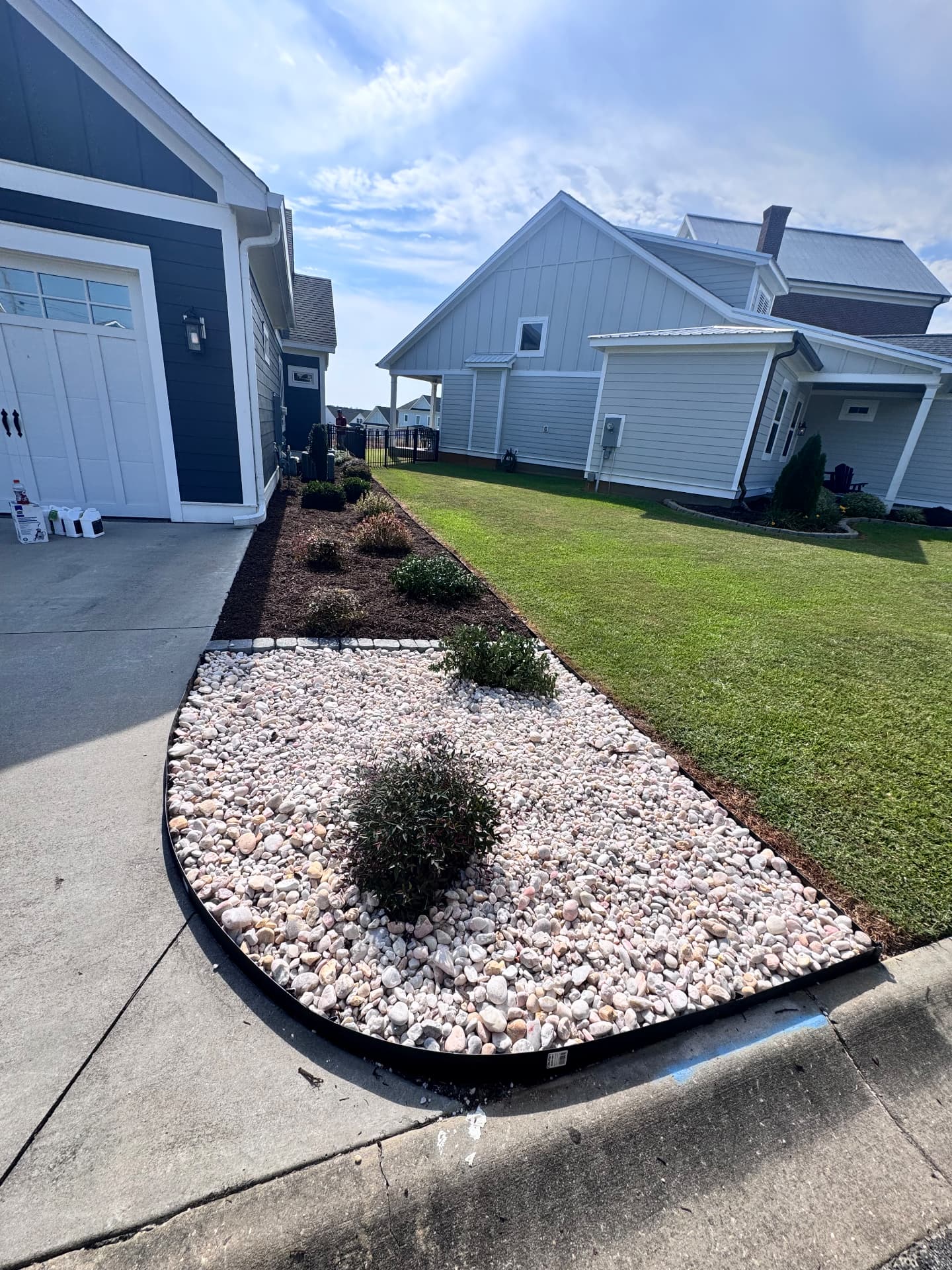 Fresh mulch beds with river rock and steel edging.