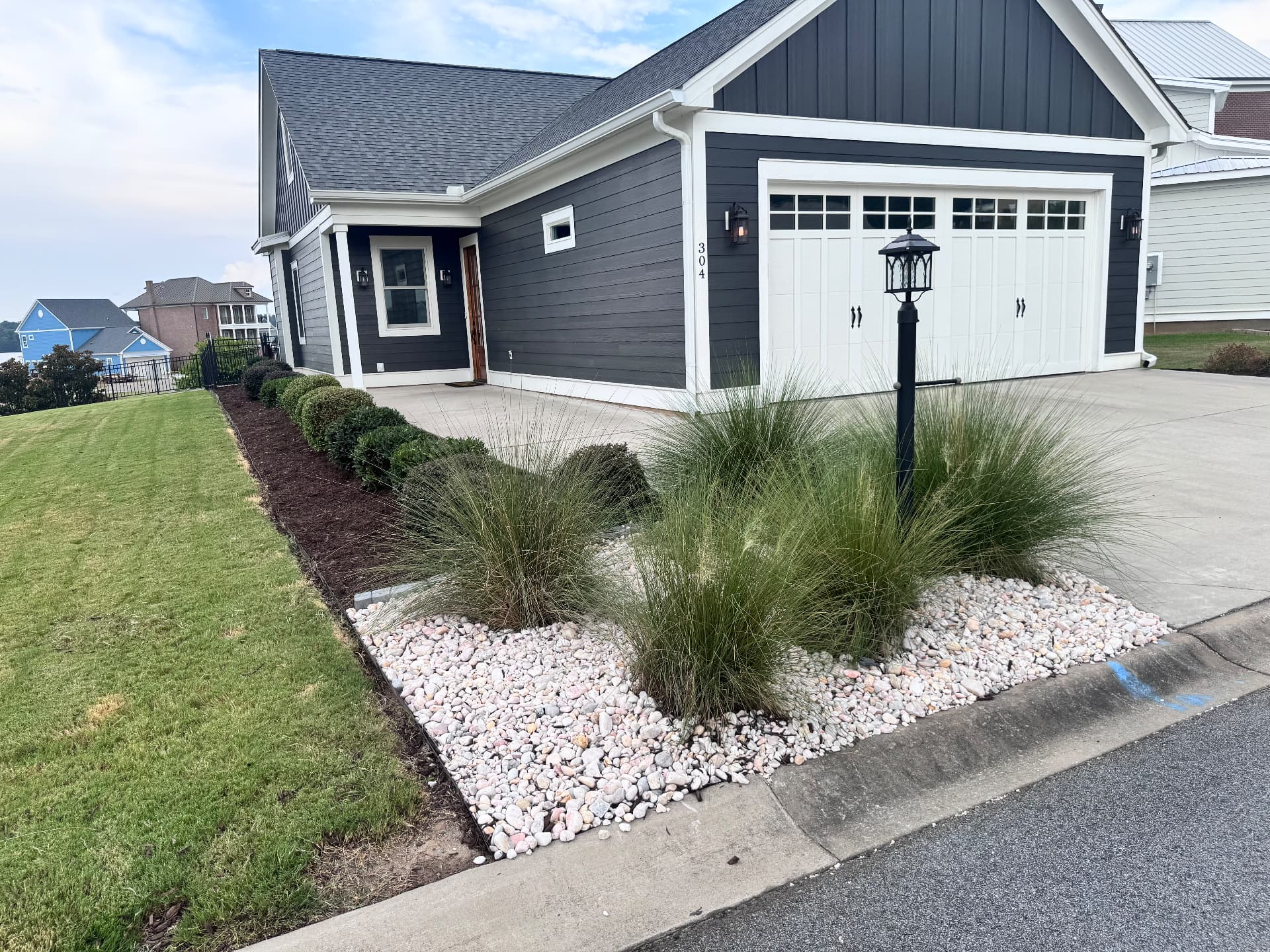 White rock bed with ornamental grasses and fresh mulch.